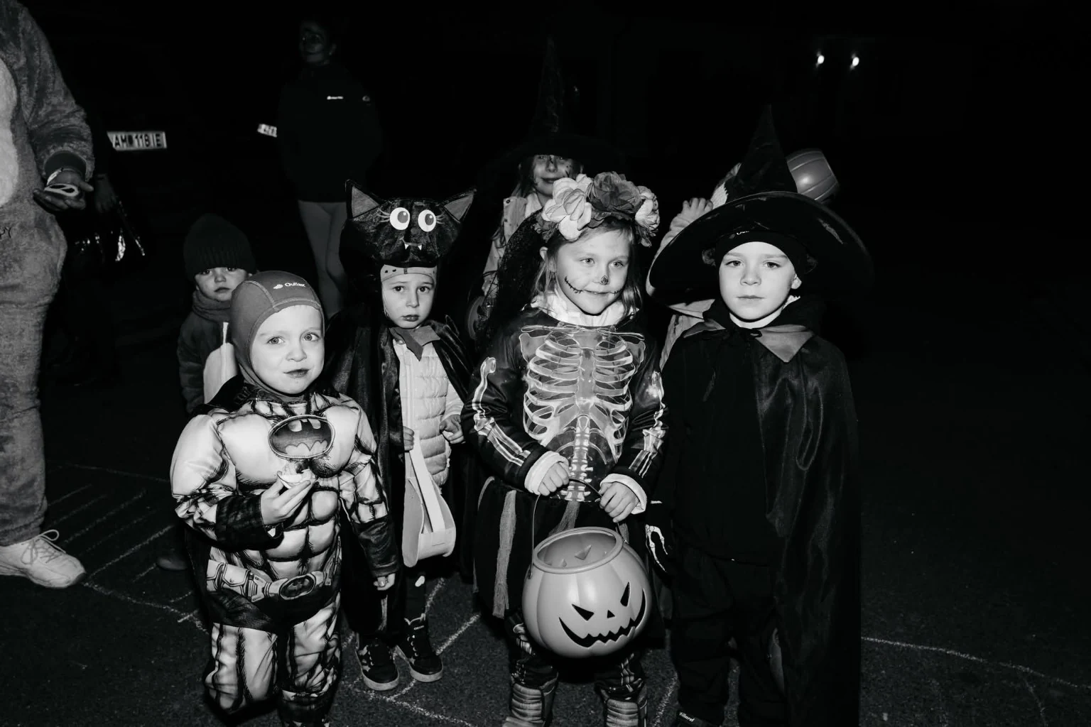 Skupina dětí v kostýmech s dýňovým košíkem během Halloweenu.